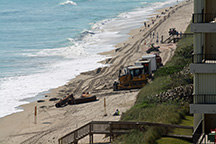 bulldozers pushing sand on the beach