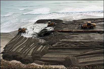 Bulldozers moving fresh sand on the beach