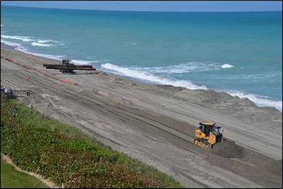 two bulldozes leveling sand on the beach