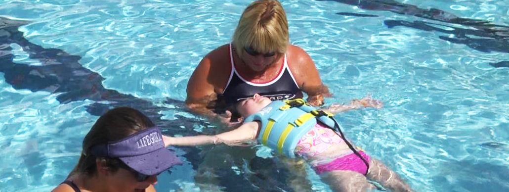 Swimming instructor teaching young girl to float on back