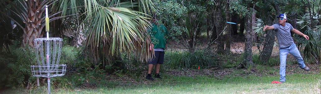 Disc golfer putting into basket at Gordy Road Preserve