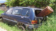 Broken down vehicle overgrown with weeds