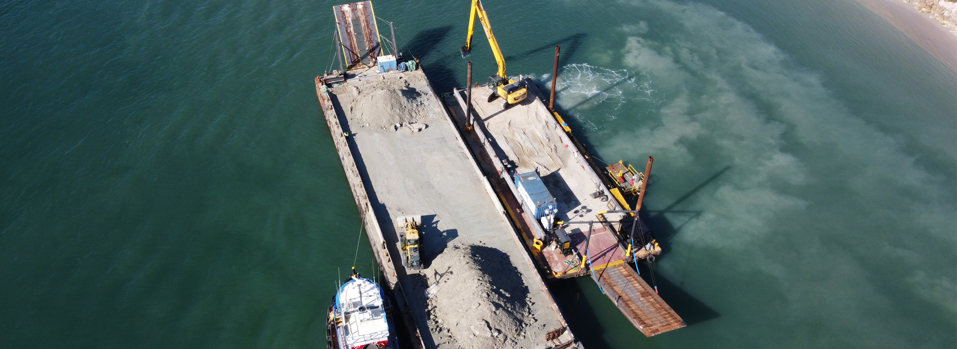 barge and dredge digging the sand bypasss trap in the fort piercce inlet