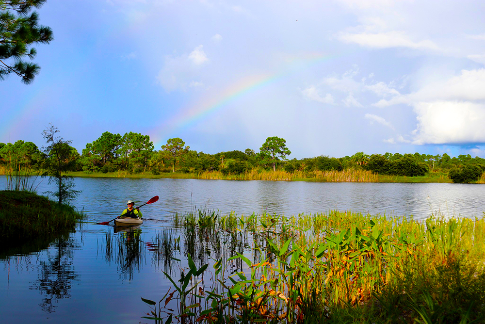 kayaker in lake with rainbow